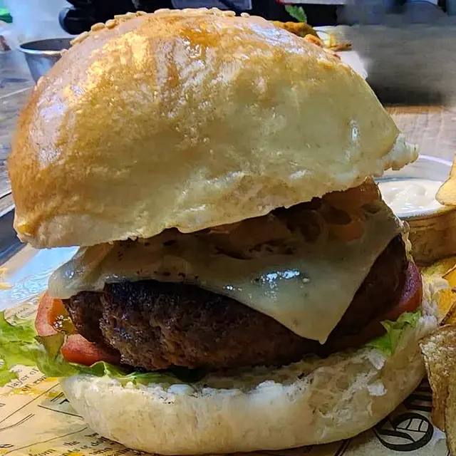 Thick burger with melted cheese on a toasted bun with potato chips